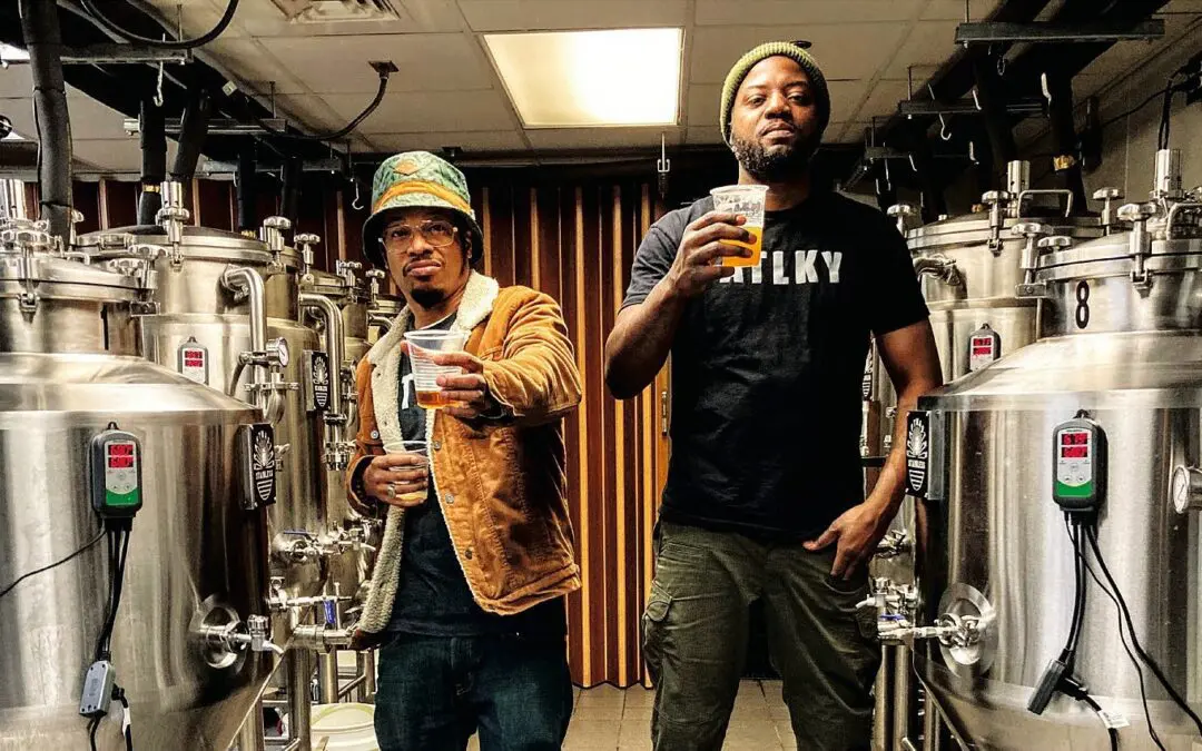 Two men standing next to each other holding beers.