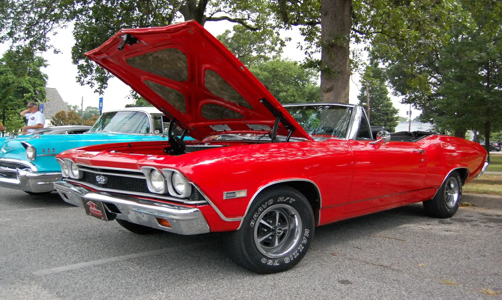 A red car with its hood open parked on the street.