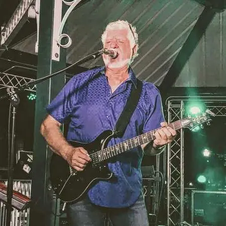 A man with a guitar and microphone in front of a crowd.