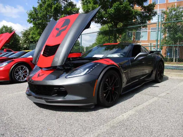 A black and red corvette parked in the street.