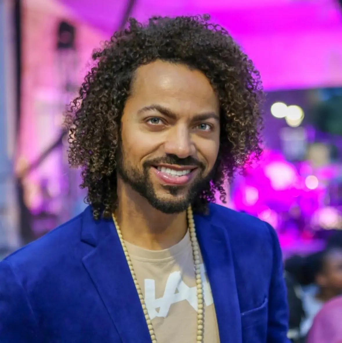 A man with long hair and beard wearing a blue jacket.