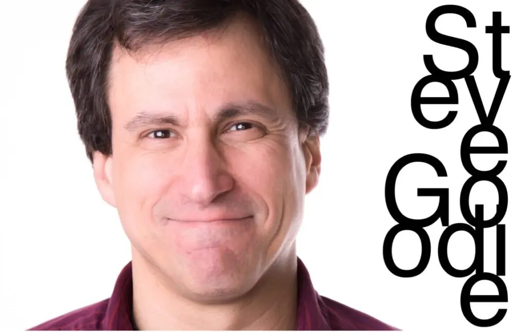 A man with a goofy smile and the words " go "