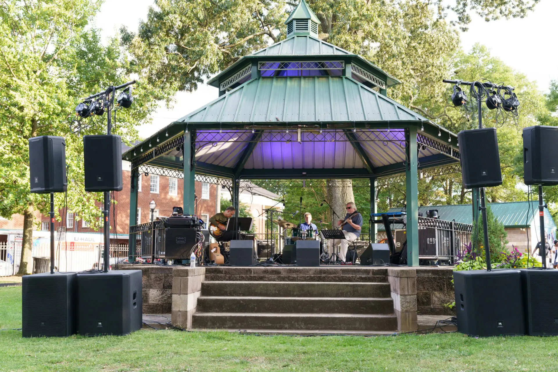 A band playing in the shade of a gazebo.