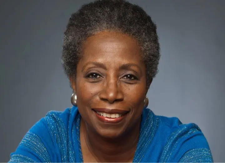 A woman with short hair and wearing blue is smiling.