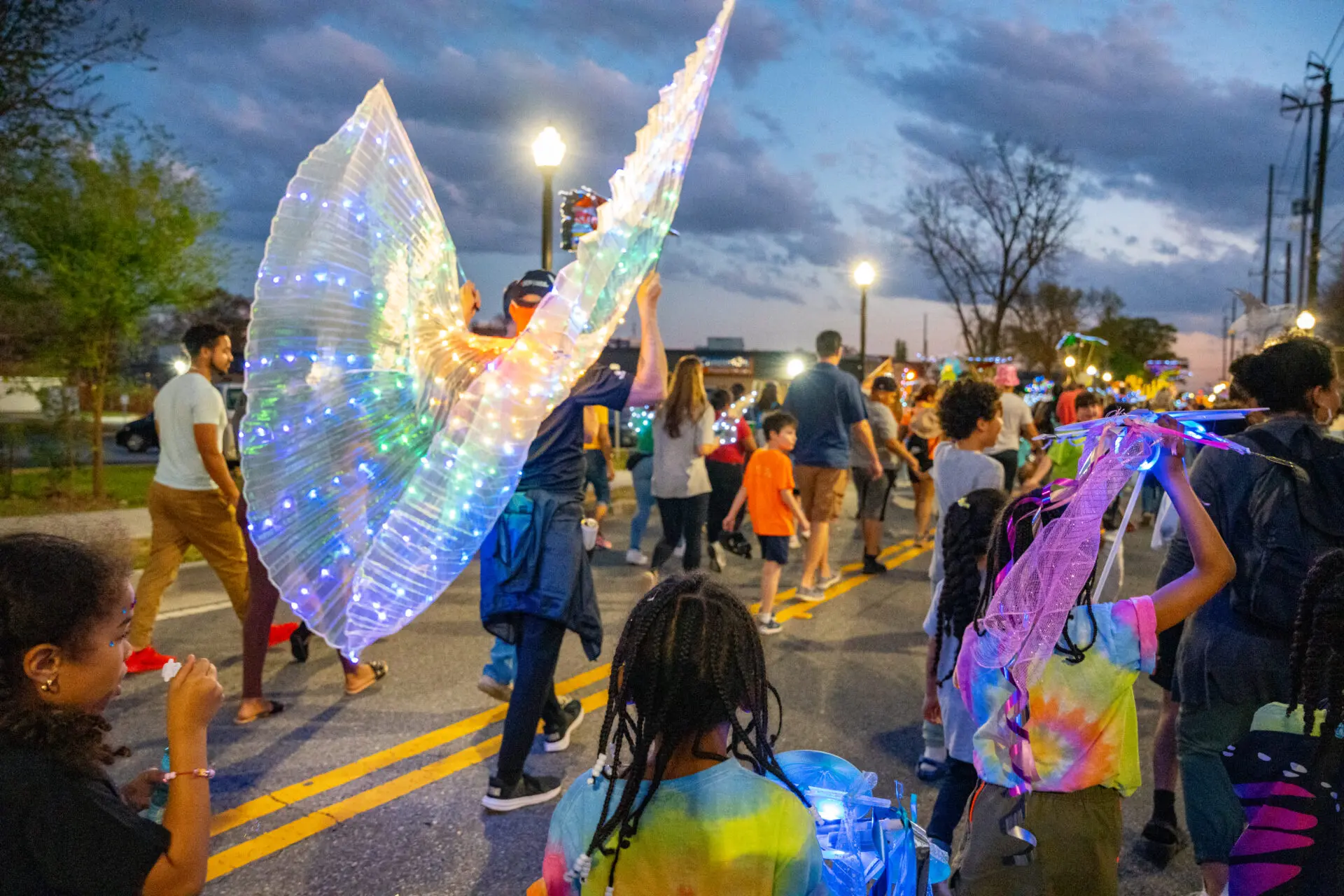 A group of people walking down the street holding up lights.