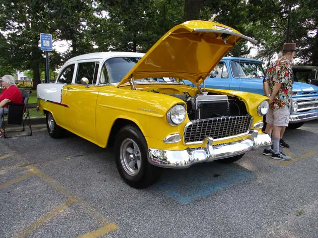 Yellow vintage car with hood open.