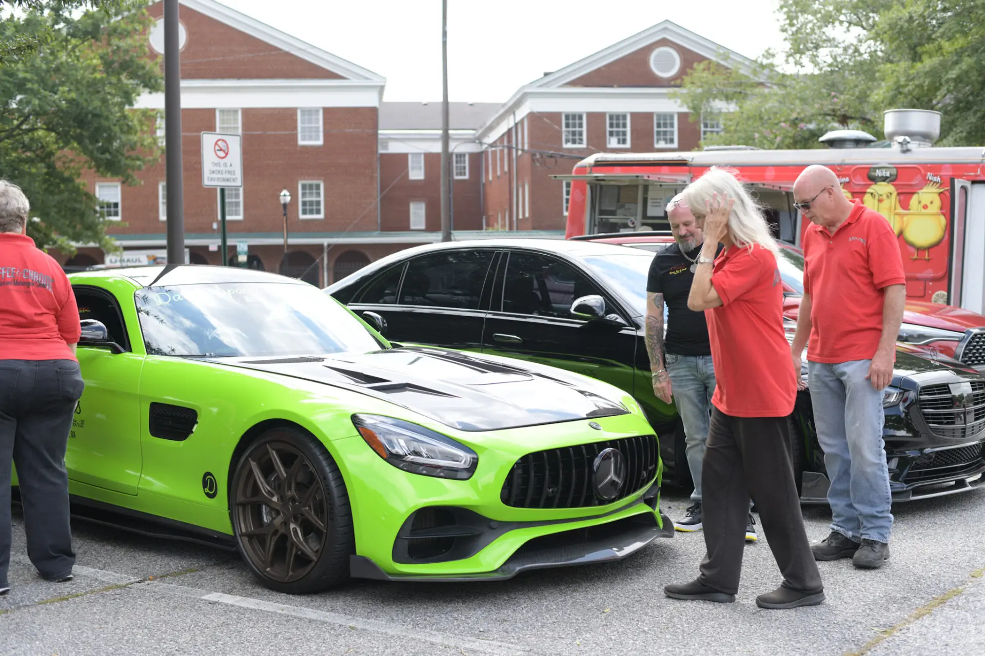 Green sports car with onlookers in parking lot.