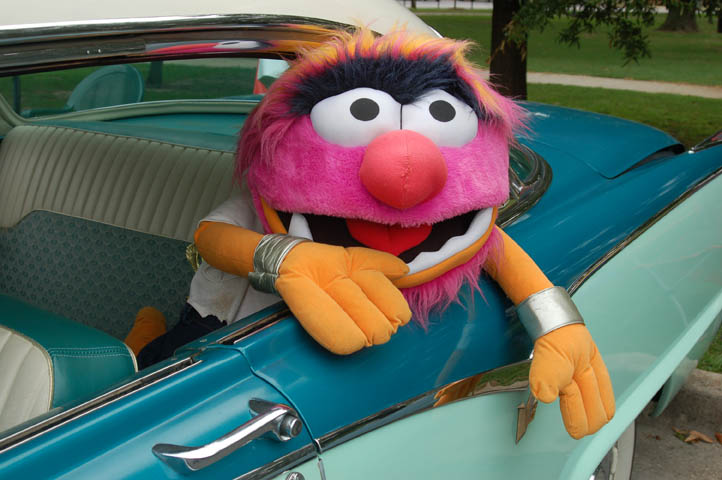 Puppet character leaning out of vintage car.